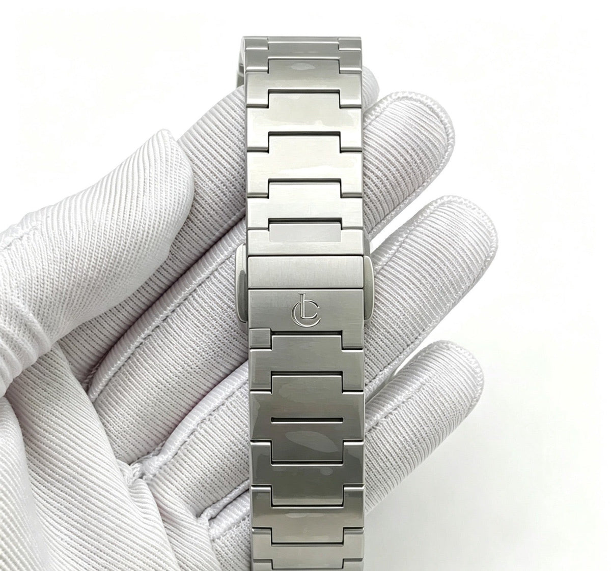 Close-up of LeeCo Errington steel bracelet clasp engraved with the LC logo, held in a white glove